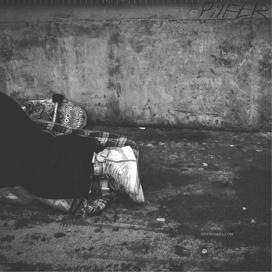 Navigating Grit in Homelessness Advocacy_B and W Photo of Homeless Youth Asleep on Ground with Skateboard next to his feet.